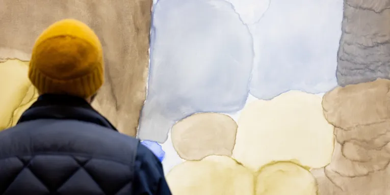Ein Mann steht mit dem Rücken zur Kamera und besucht eine Kunstausstellung.